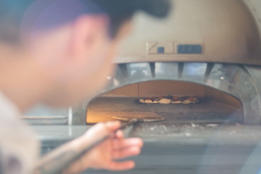 Chef surveillant la cuisson d'une pizza dans un four à bois traditionnel