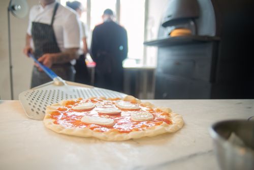 Free A chef places a pizza onto a peel in a traditional Portuguese kitchen, ready for baking. Stock Photo