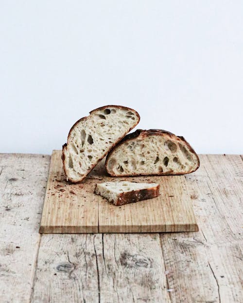 Pieces of homemade crispy bread with crumbs on wooden cutting board on table