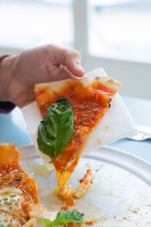 Free Savor the delicious taste of a classic Margherita pizza slice with fresh basil. Stock Photo