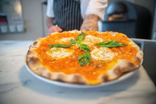 Free Close-up of freshly baked Margherita pizza with basil on a marble countertop. Stock Photo