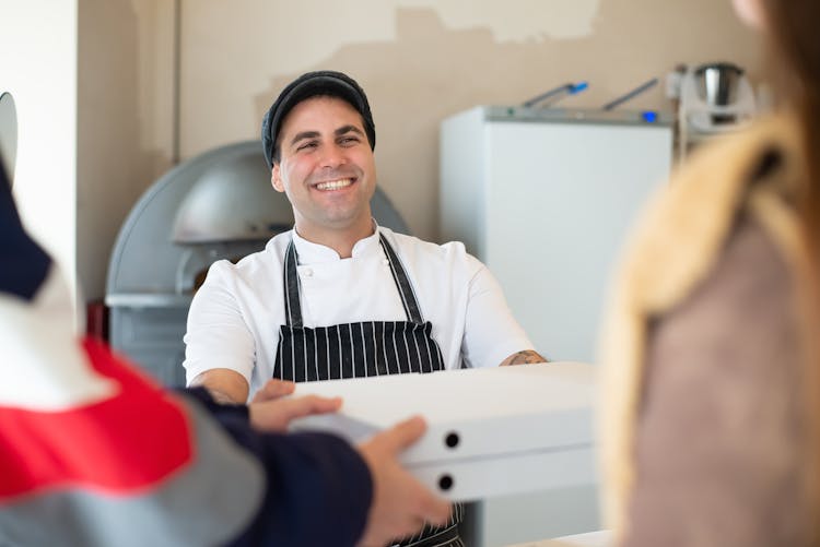 Happy Baker Giving Boxes Of Pizza To Customers