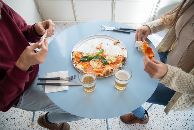 People Sitting On A Table Eating Pizza