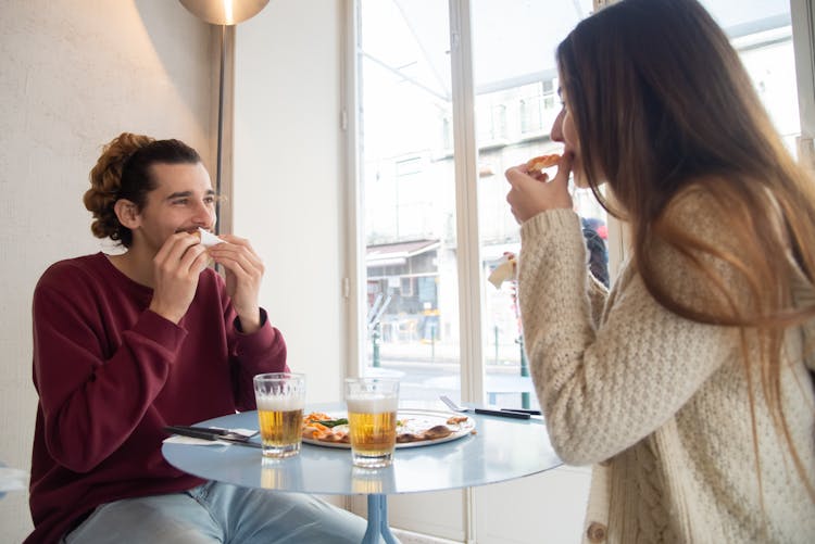 Man And Woman Eating Pizza In Restaurant