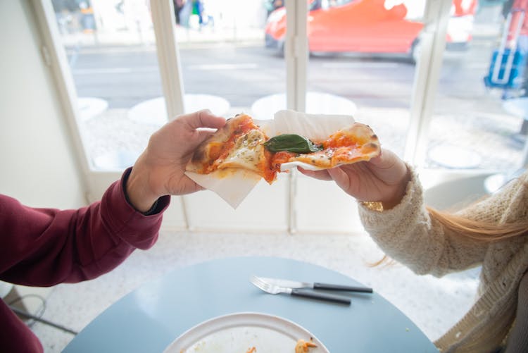 Hands Holding Pizza Slices 