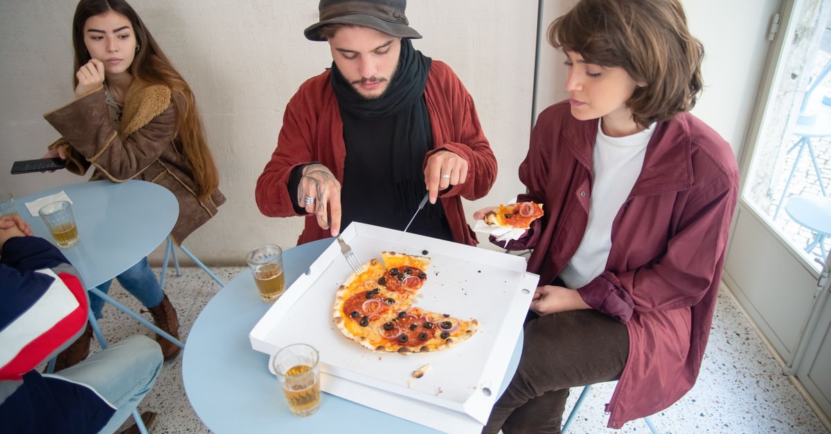 Groupe de jeunes adultes dégustant de la pizza dans un café. Ambiance décontractée et tenue élégante.