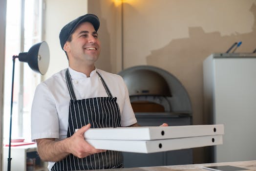 Smiling chef in apron holding pizza boxes in a Portuguese restaurant.