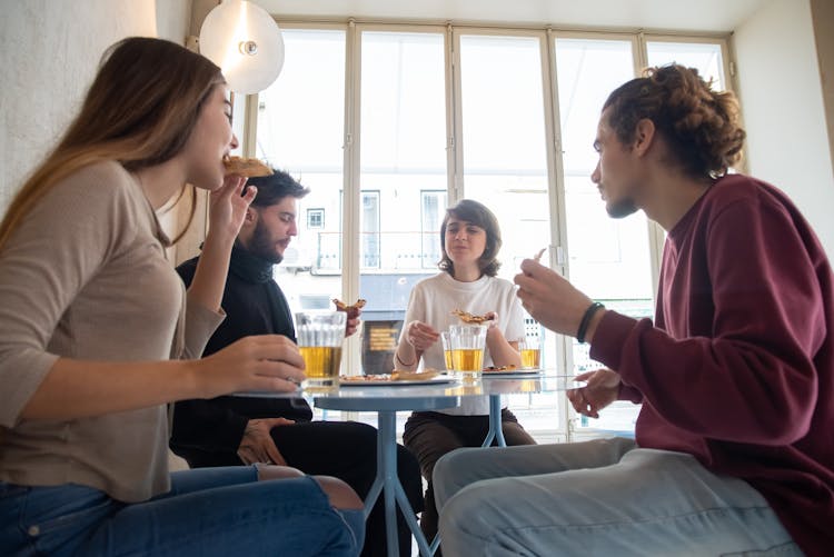 A Group Of People Eating Near The Window 
