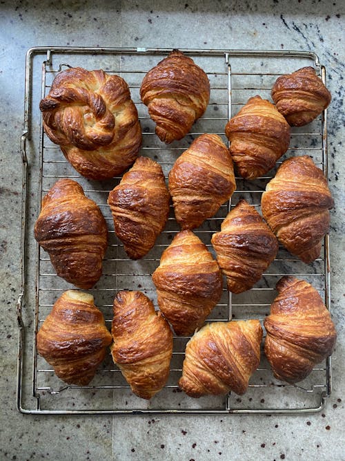 Free From above of many fresh baked sweet croissants served on metal stand after baking on marble table in light kitchen Stock Photo