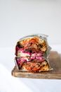 Tasty sub sandwich cut in half with delicious filling with meat wrapped in package placed on wooden board on white background