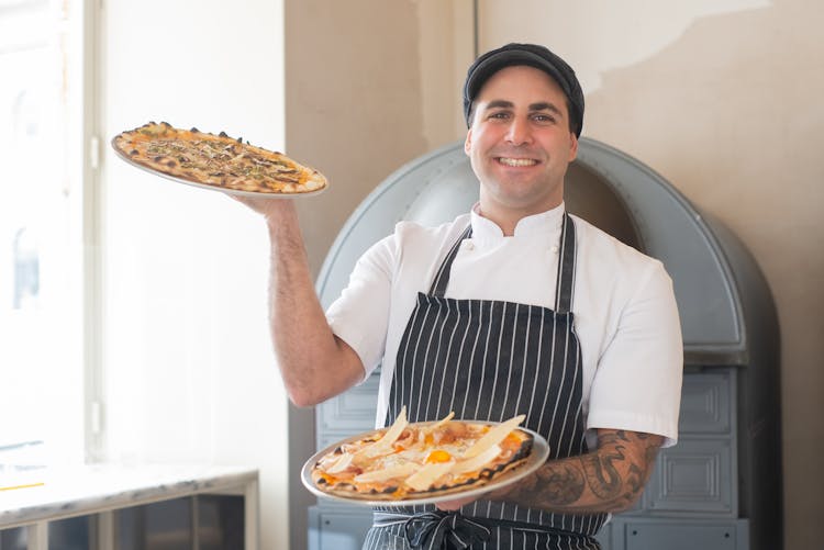 Portrait Of Smiling Man Holding Pizzas 