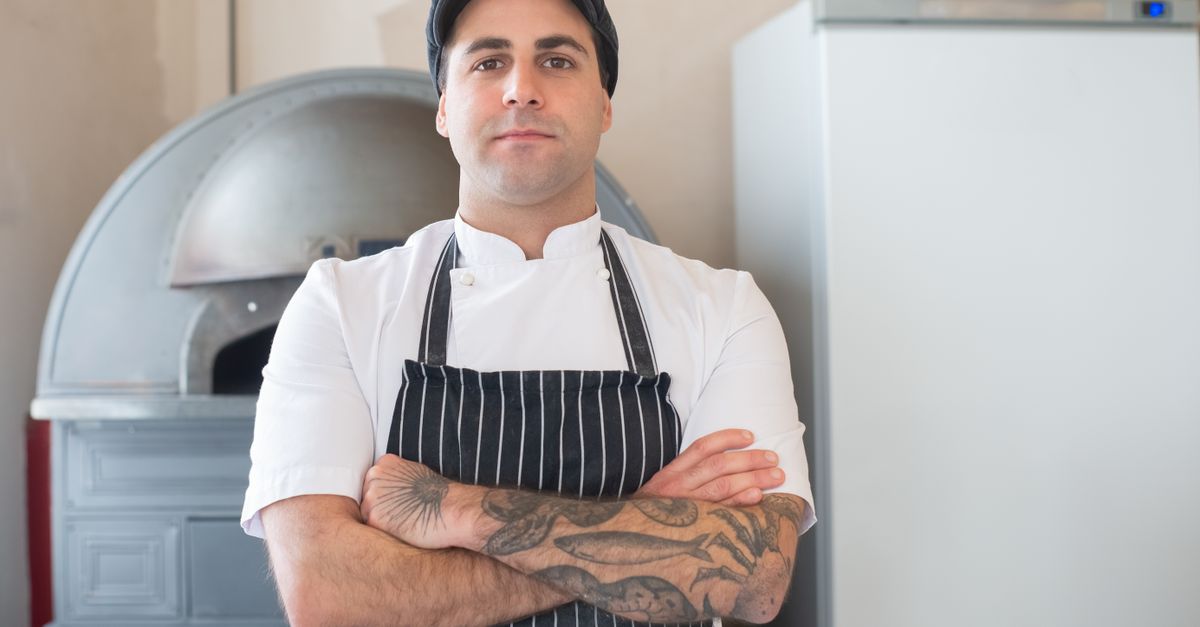 Two chefs in a heated debate in a professional kitchen, one holding a jar of MSG, the other crossing arms