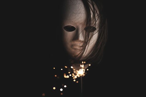 Free A mysterious and eerie scene of a mask with a sparkler, set against a dark background, creating a haunting ambiance. Stock Photo