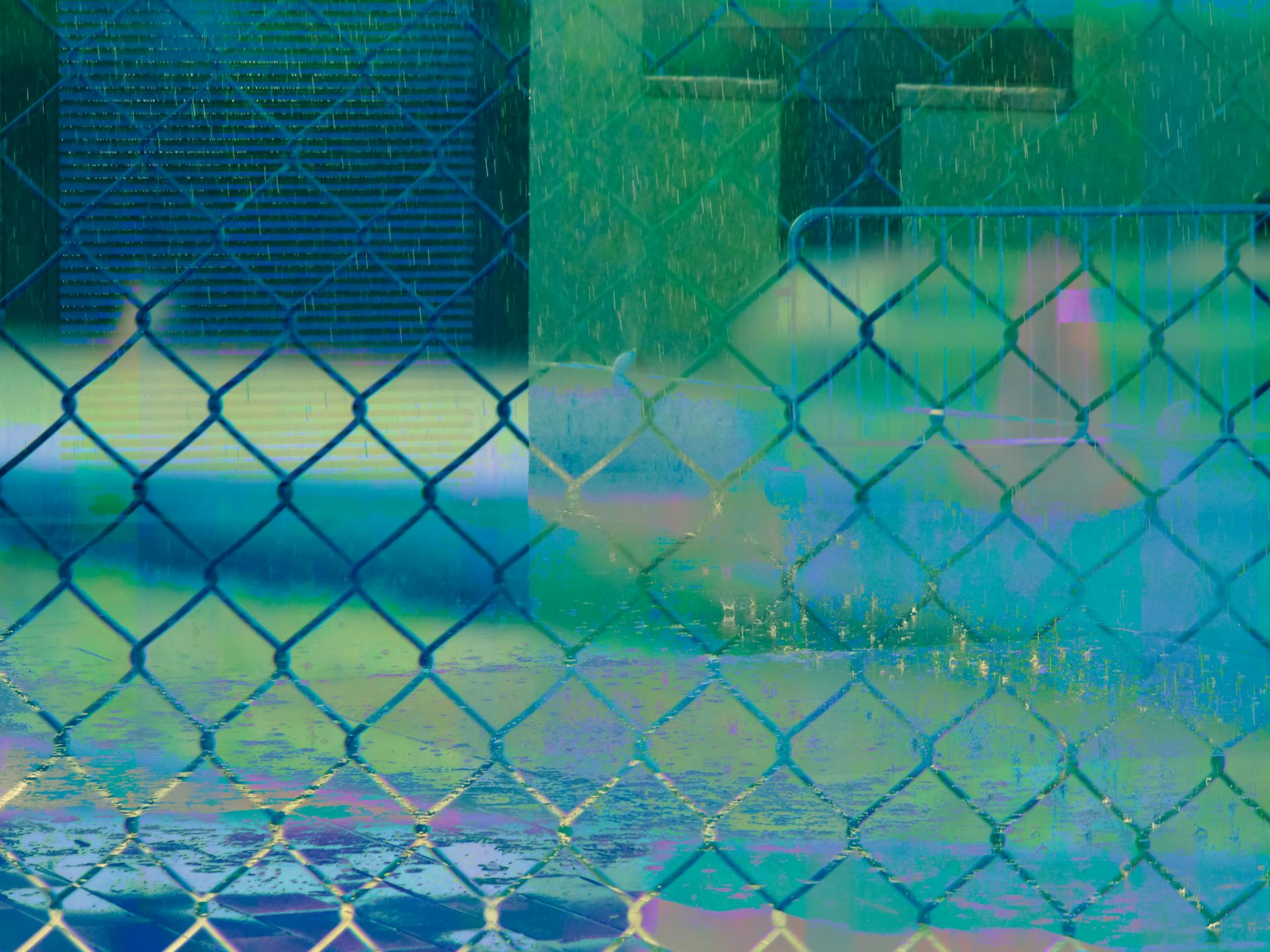 Colorful abstract view of rain through a chain link fence creating a unique visual texture.