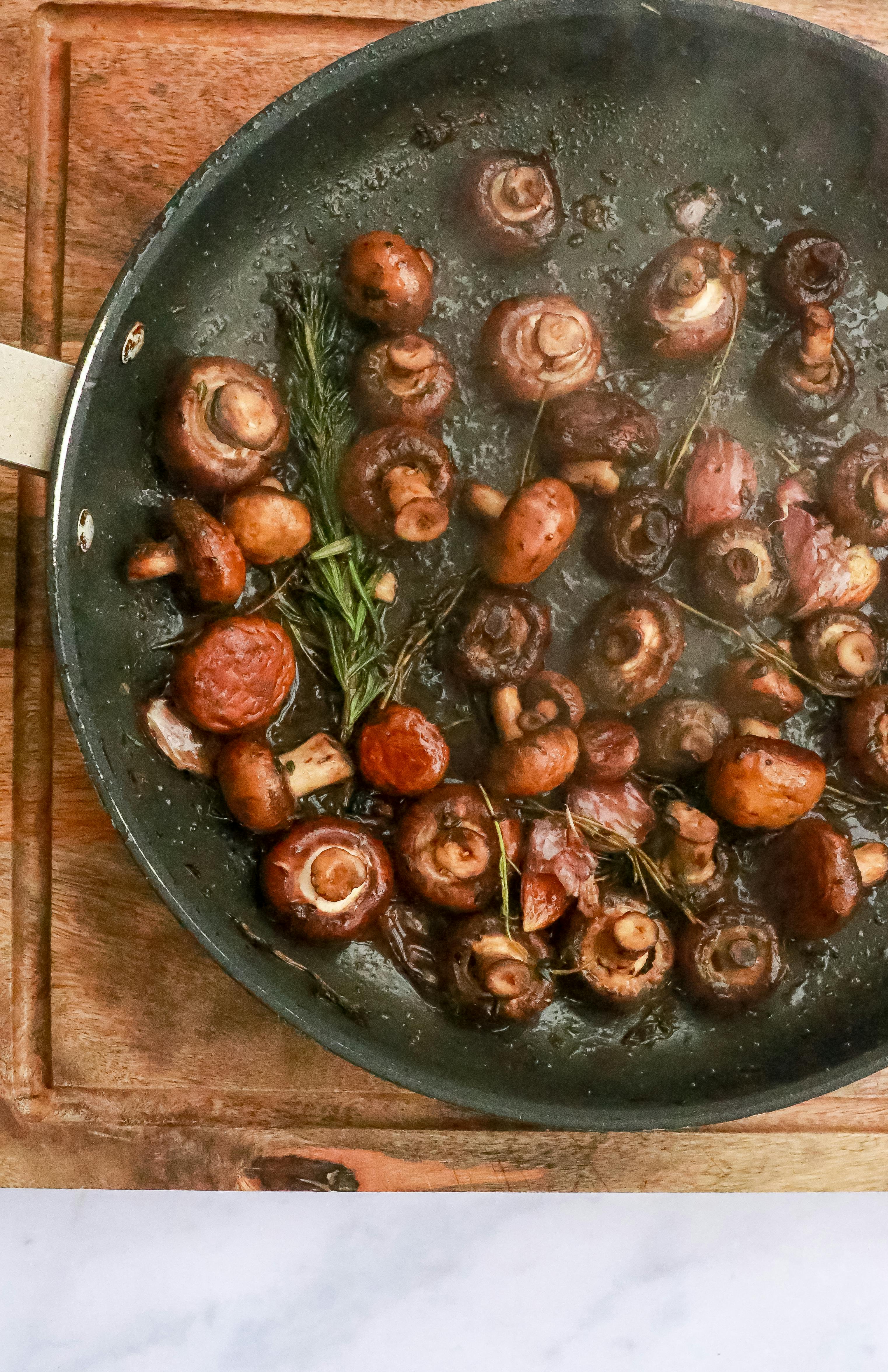 frying mushrooms with rosemary in pan