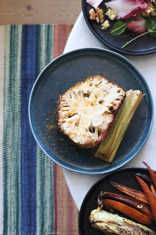 Delicious cauliflower dish placed on table near grilled carrots