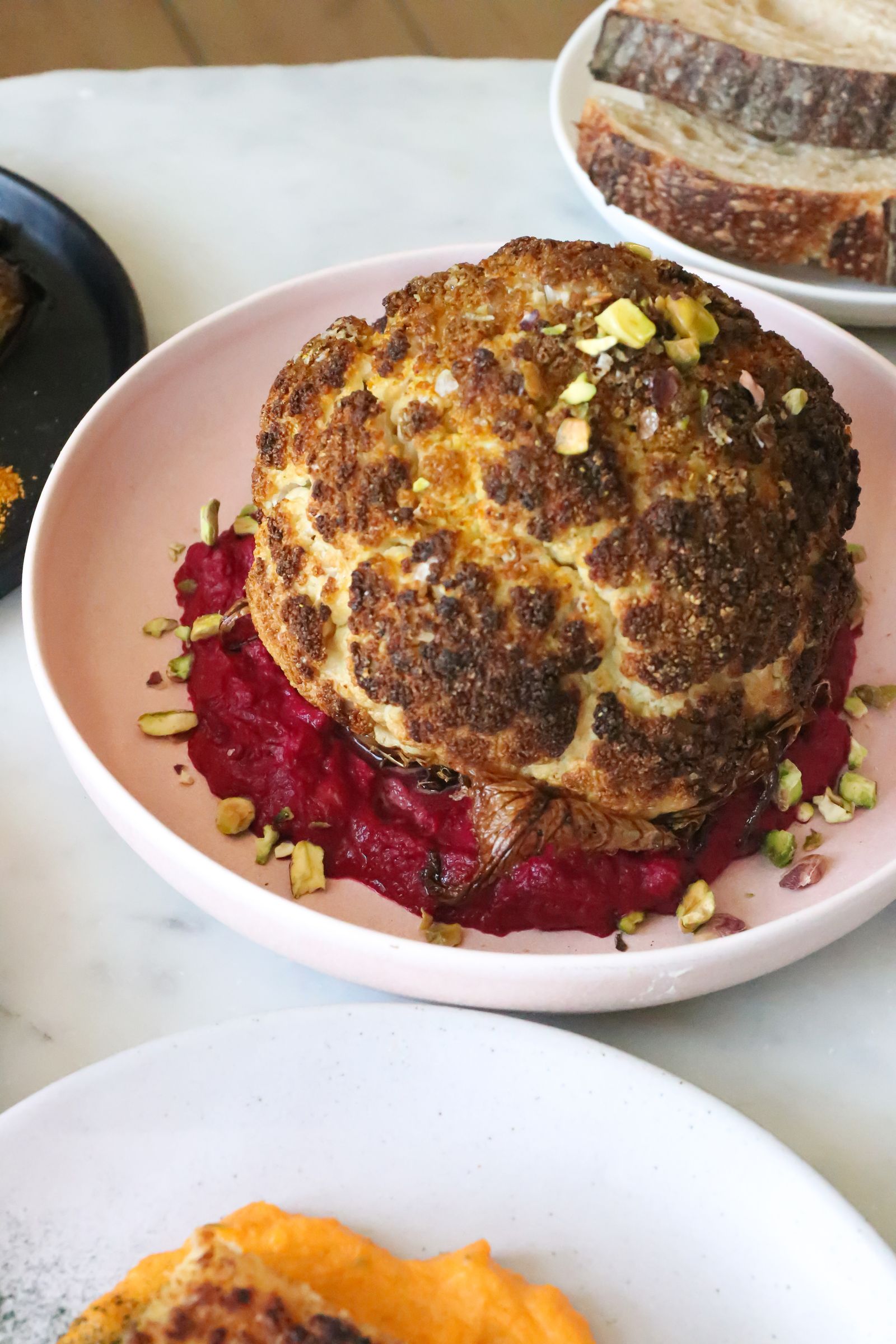 Hele geroosterde bloemkool op een saus-spiegel, restaurantwaardig opgemaakt.