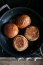 From above of fresh buns for burger frying on hot pan on stove in daytime
