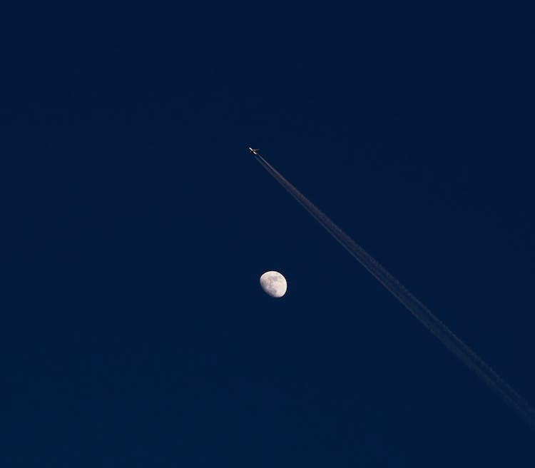 Airplane Flying High And Leaving A Trail On A Night Sky 