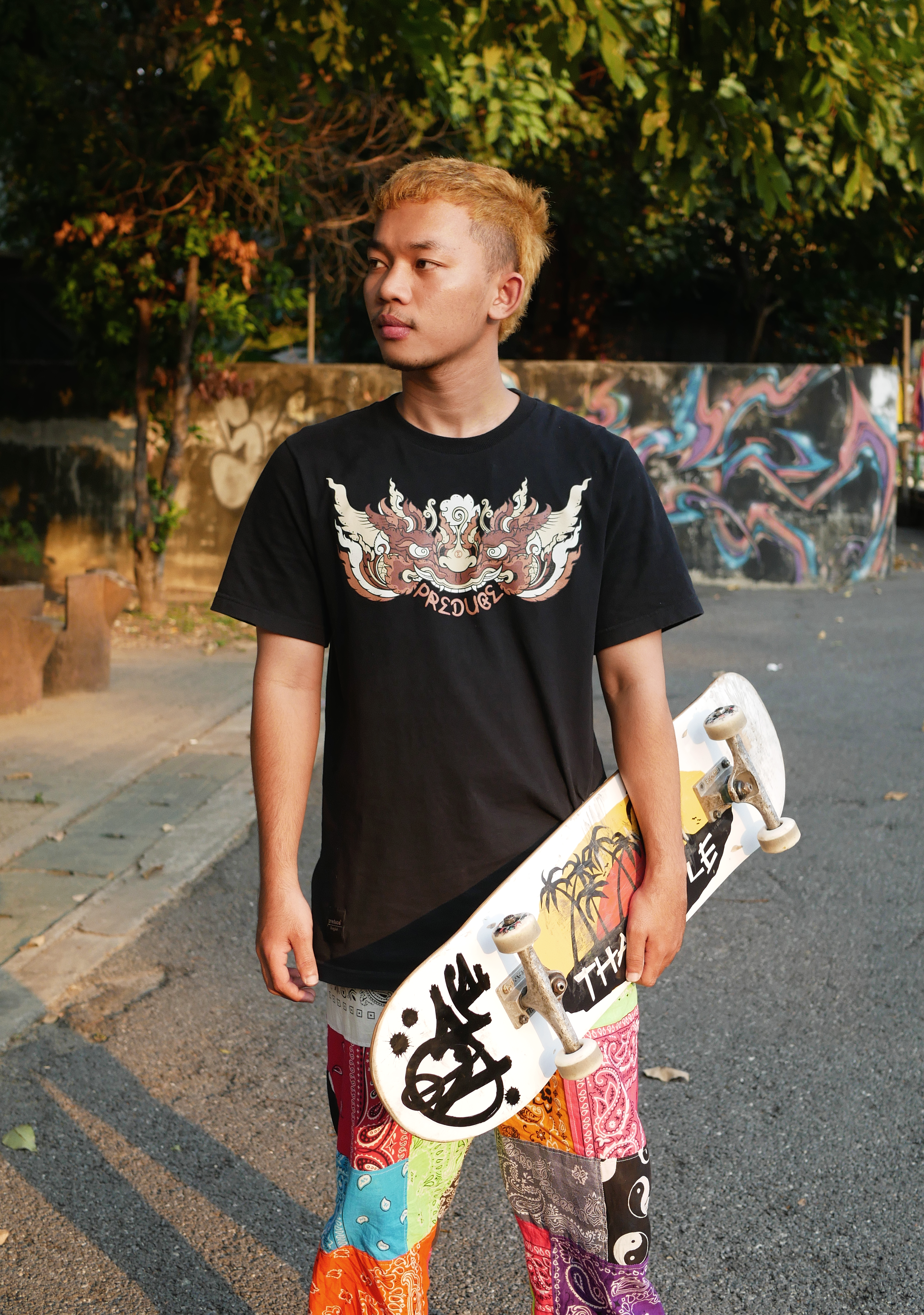 A young male skater holding a skateboard in a vibrant urban setting, capturing street culture.