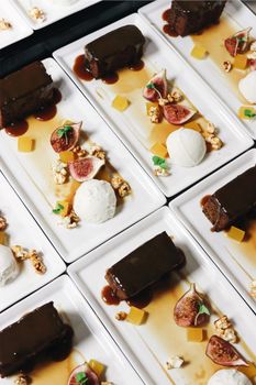 From above of delicious desserts on plates with ice cream scoop near figs and chocolate cake decorated with syrup placed on surface in light restaurant