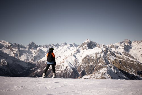 A Person Wearing a Helmet on a Snow Covered Ground Near a Snow Covered Mountain