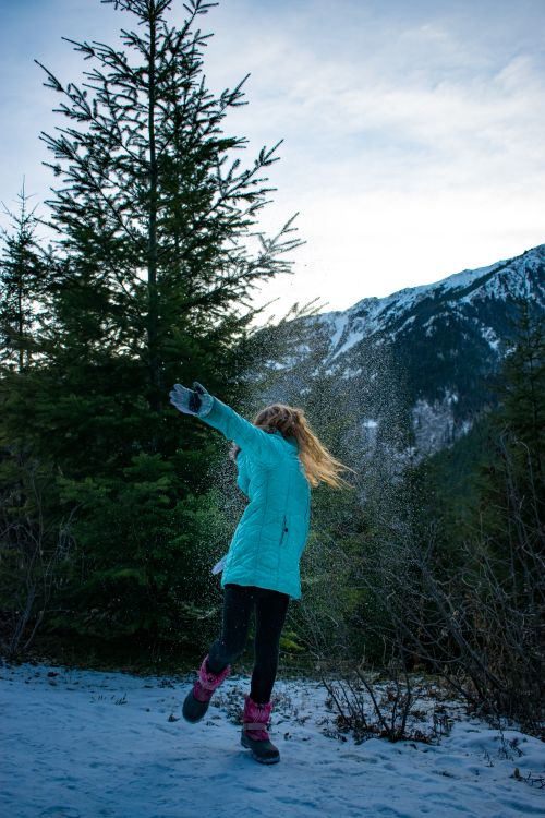 Free A woman dances joyfully in a snowy evergreen forest with mountain views in Washington state. Stock Photo
