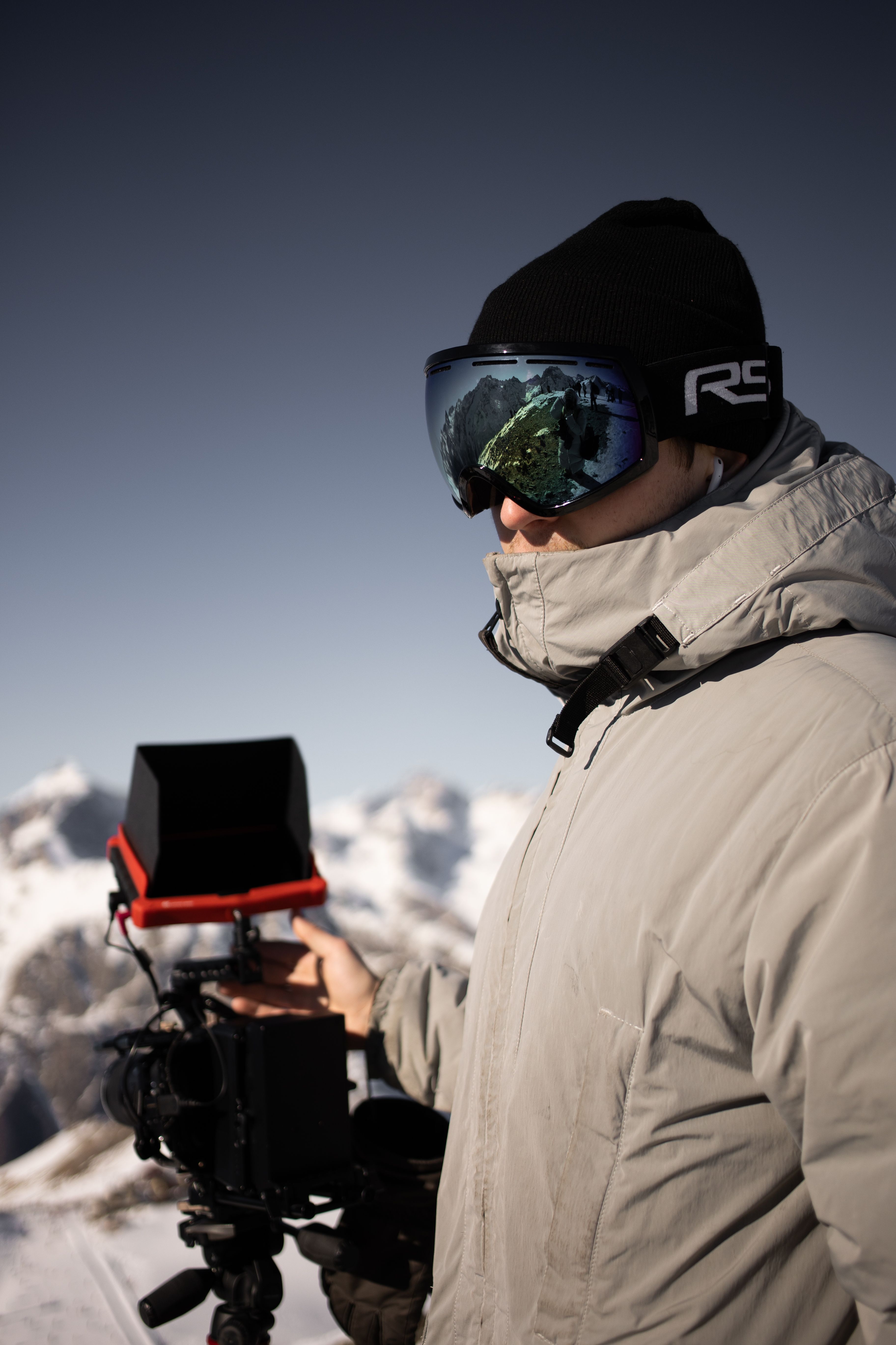 A professional photographer in winter gear capturing stunning snowy mountain landscapes.