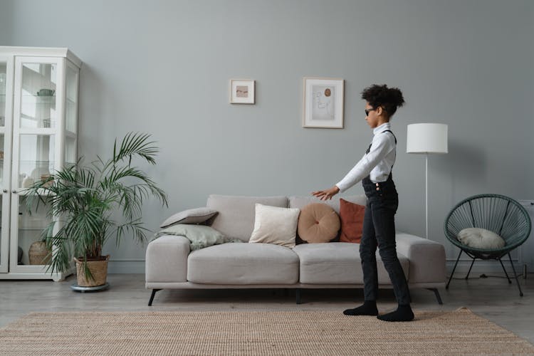 A Child Wearing Sunglasses Walking On A Rug Beside A Sofa