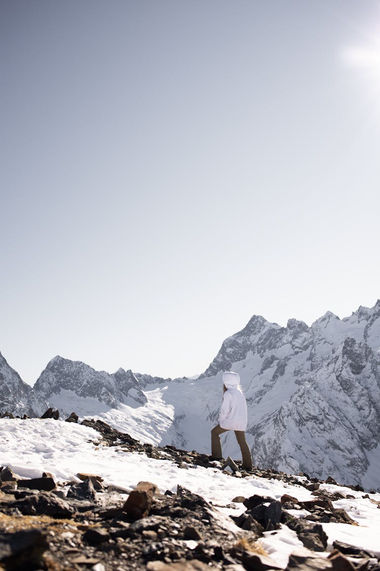 Person In White Hoodie Walking On Rocky Mountain