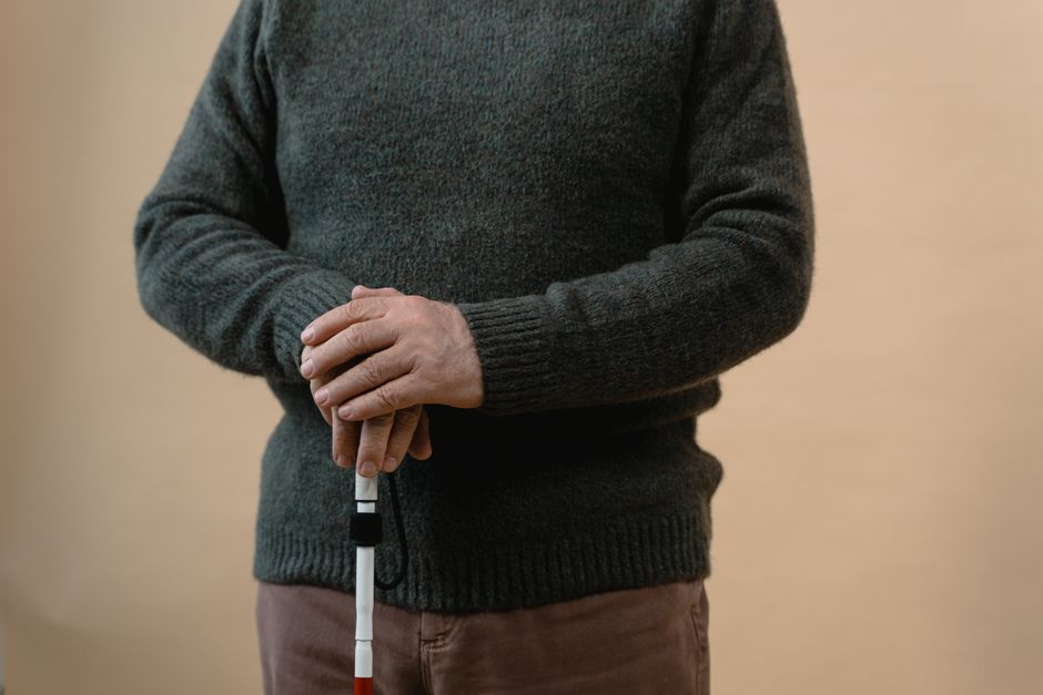 장애인 복지카드 혜택과 신청 절차, 사용 꿀팁 13 A man in a sweater holding a white cane, symbolizing vision impairment.