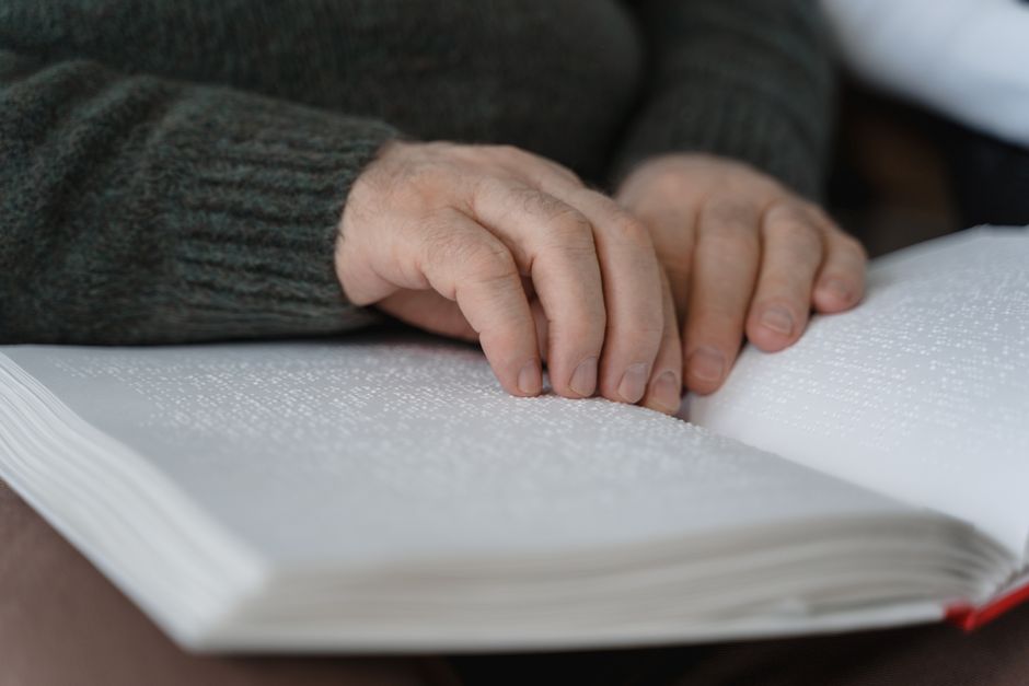 Close-up of hands reading a braille book, emphasizing accessibility and tactile learning.
