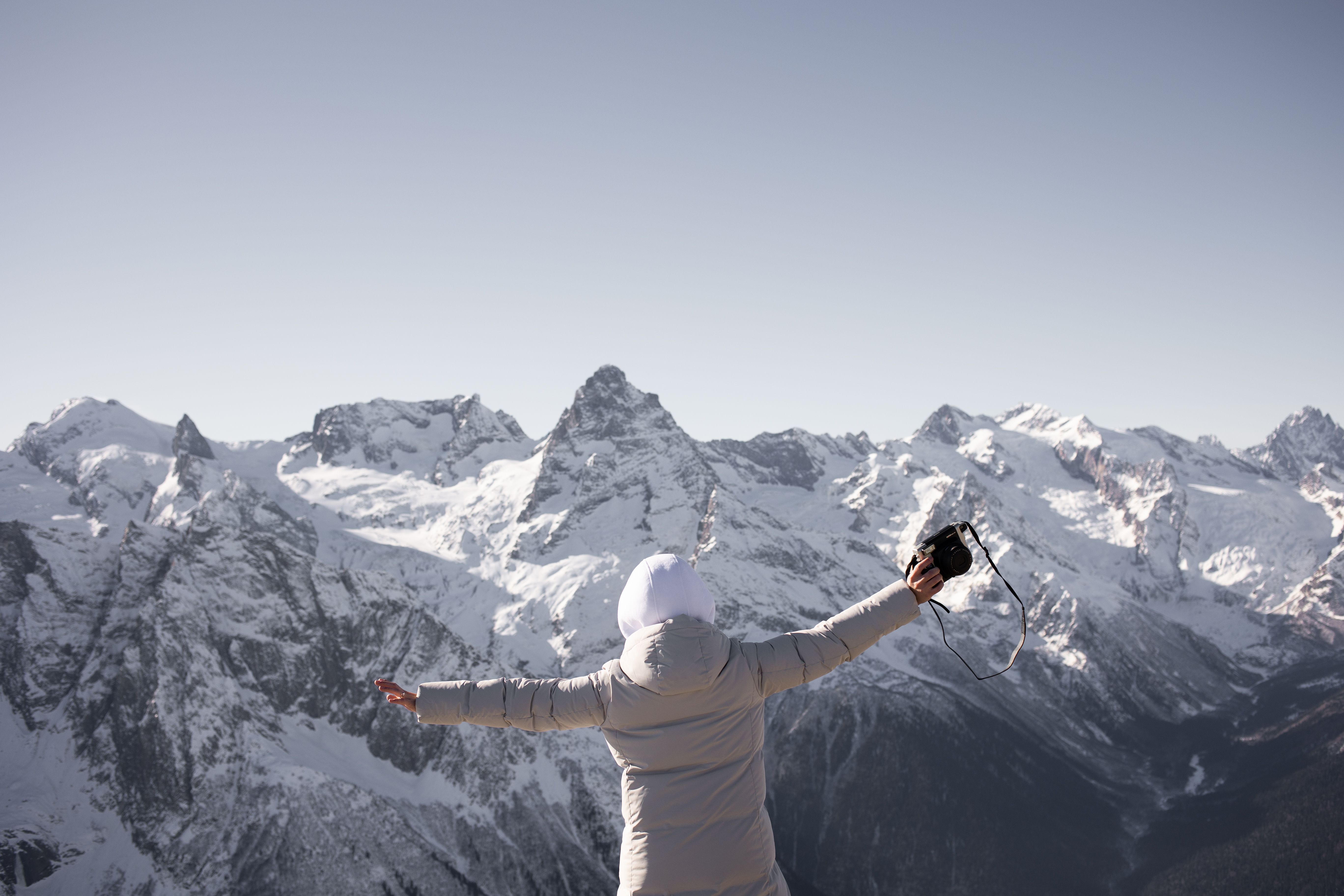 Person enjoying a snowy mountain view, capturing the moment with a camera.