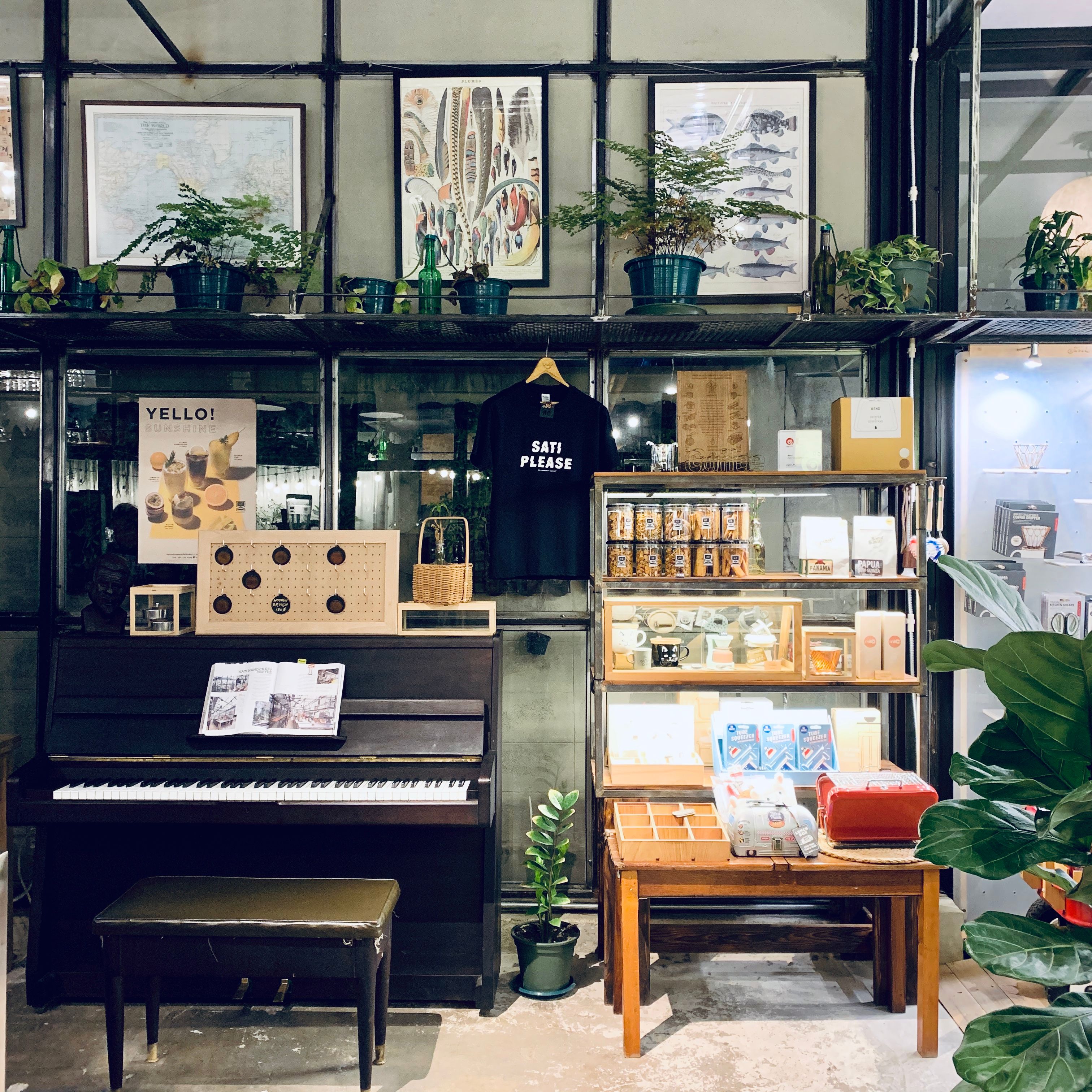 Stylish store interior showcasing plants, a piano, and a variety of merchandise on shelves.