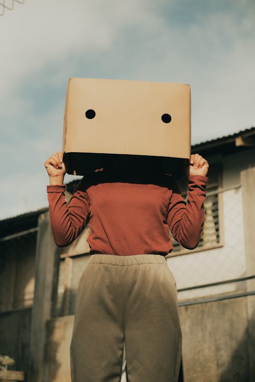 Anonymous woman with box on head near building