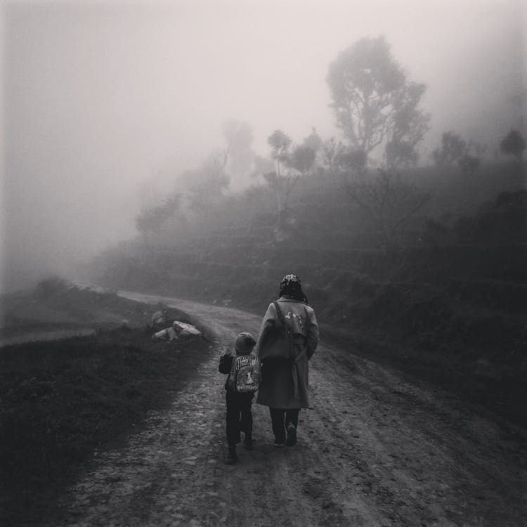 A Mother And Son Walking On Dirt Road