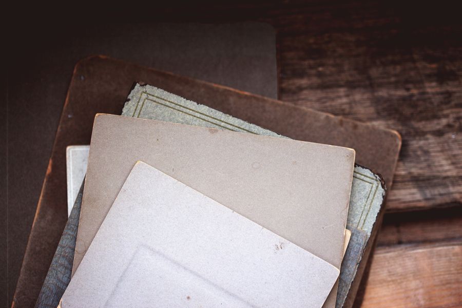 Close-up of a stack of vintage papers with discoloration on a wooden table, creating an antique feel.