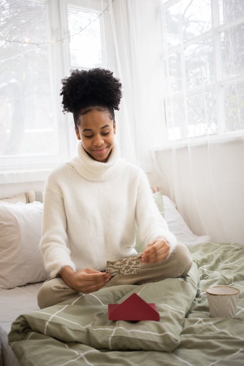 Free A Woman Sitting on the Bed Holding a Card Stock Photo