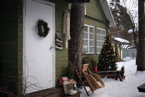 A Wooden Sledge Leaning on a Tree Outside a House with Christmas Decorations