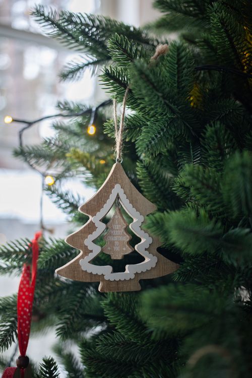 Free Close-up of a wooden tree ornament hanging on a decorated Christmas tree with lights. Stock Photo