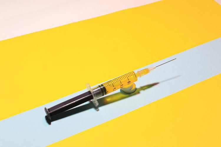 A Syringe With Liquid Over Round Pills