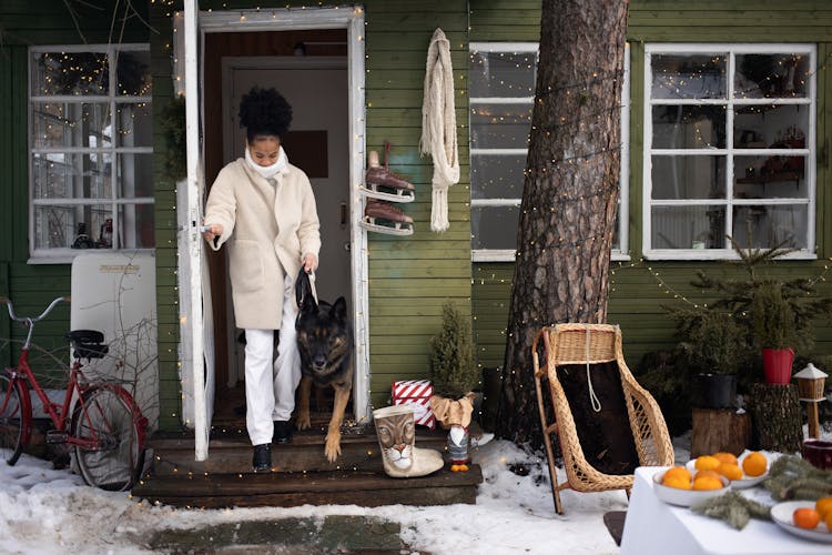 A Woman And A Dog Walking Out Of A Door