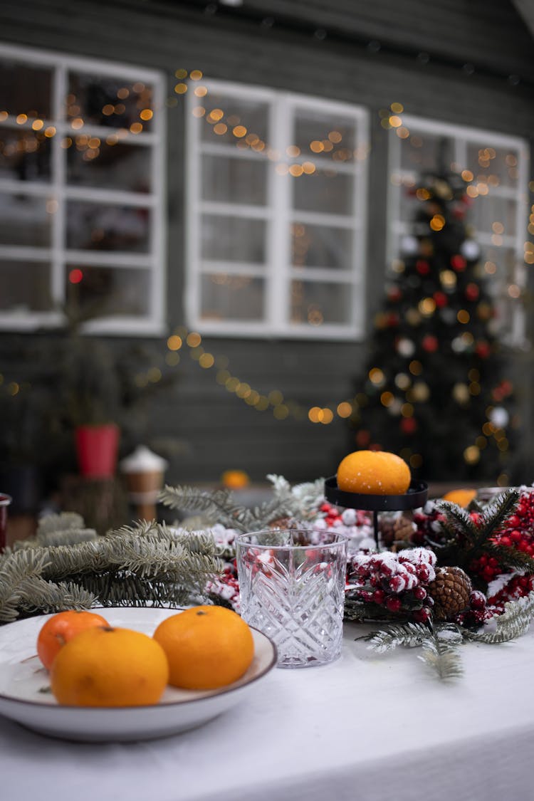 Mandarin Fruits And A Drinking Glass On A Table With Christmas Ornaments