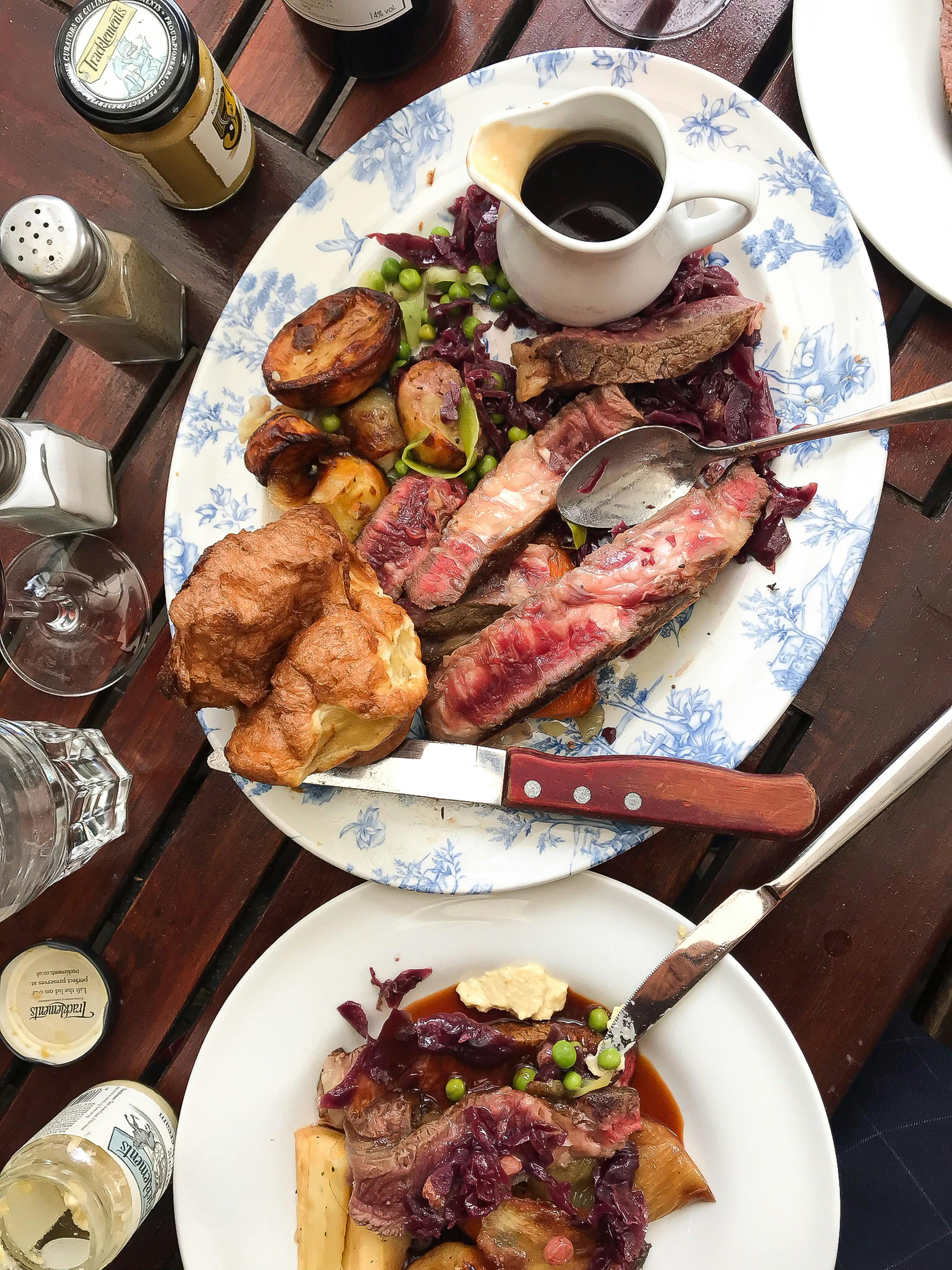 plates with grilled meat and vegetables near sauce and glassware