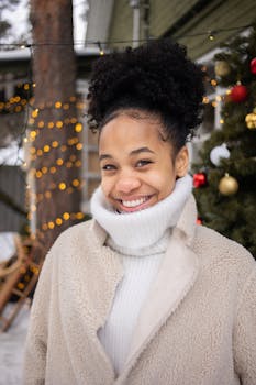 Happy woman outdoors in winter, surrounded by festive lights and decorations.