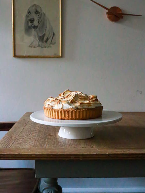 Meringue tart on cake stand on wooden table