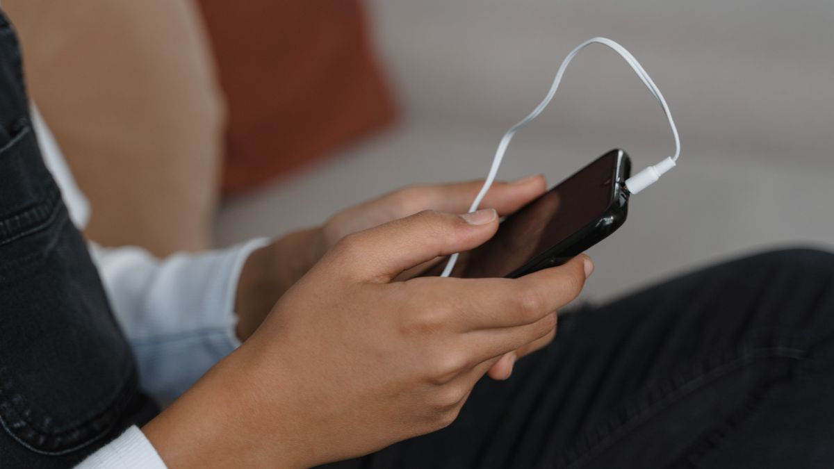 スマートフォンとイヤホンを手に持ち、音声で会話する準備をしているイメージ