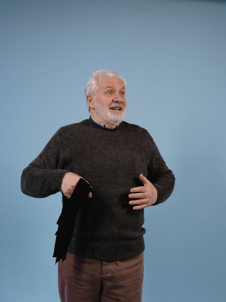 Senior Man Standing In Gray Sweater Holding A Black Cloth