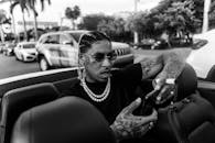 Brutal black man in car with cigarette using smartphone