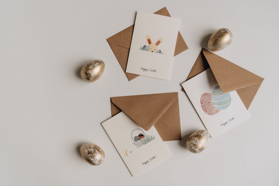 Flat lay of Easter greeting cards, golden eggs, and envelopes on a light surface. Perfect for festive celebrations.